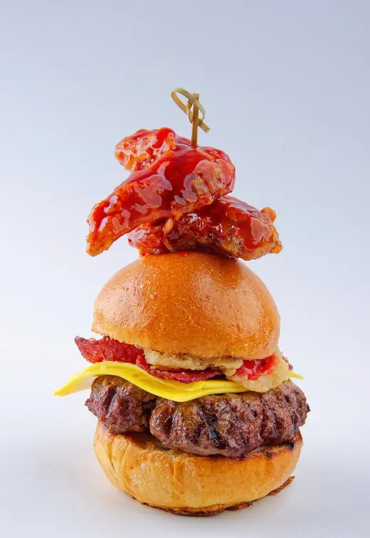 Wings Burger de Tostado, con alitas en salsa roja sobre la hamburguesa